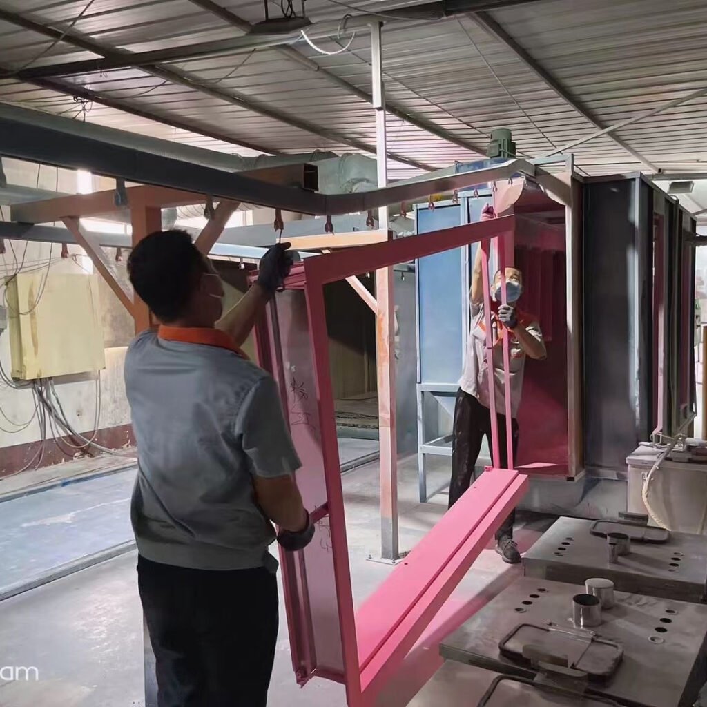 Our OSIDEK production team members loading a custom steel door frame onto the automated powder coating line in our manufacturing facility.