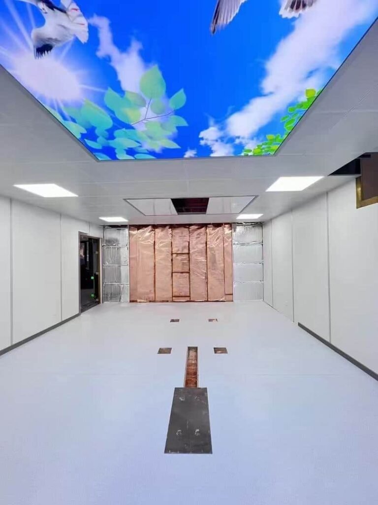 Mid-construction view of a hospital MRI room, showcasing OSIDEK's exposed copper EMI/RF shielding wall alongside a finished aesthetic blue sky ceiling.