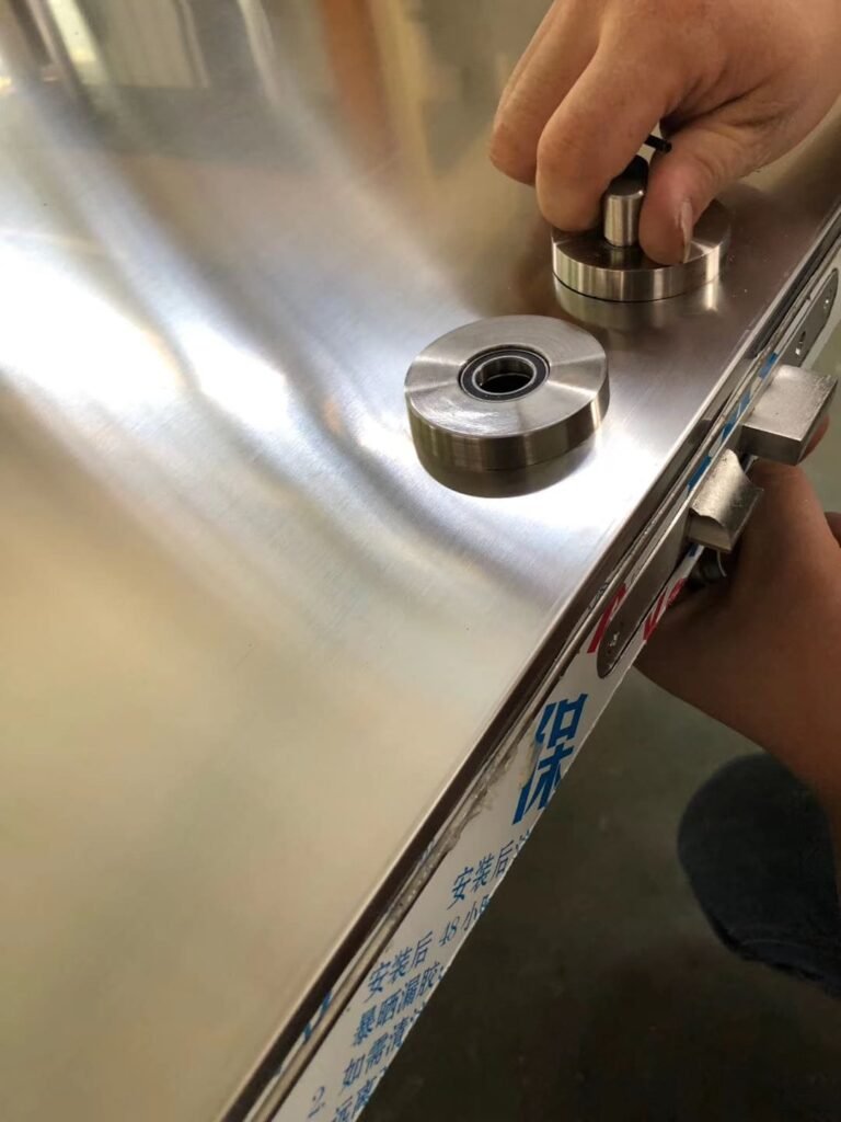 Close-up of OSIDEK independent manufacturing process, showing expert assembly of hardware on a heavy-duty stainless steel airtight door.
